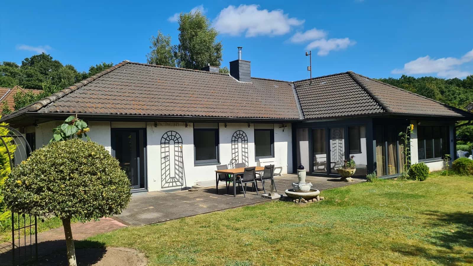 Bungalow mit Terrasse und großem Garten, unsaniert: bemooste Dachziegel, alte Rollläden und ein Wintergarten aus den Achtzigern